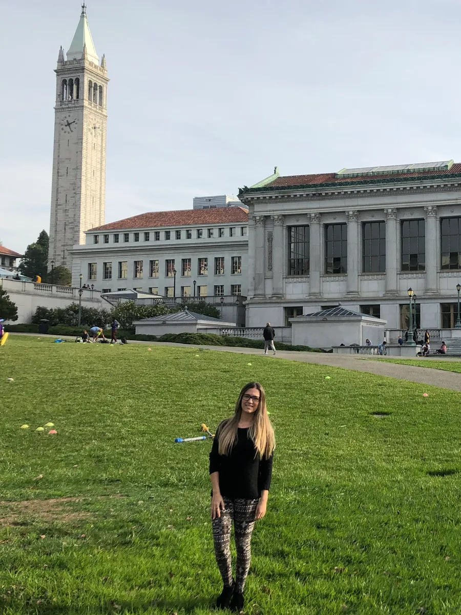 Ana on the UC Berkeley campus with Sather Tower and the University Library behind her